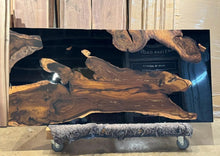 A Live Edge dining table top featuring rich, natural wood grain with raw, organic edges, contrasted by sleek black epoxy resin filling the cracks and imperfections, creating a modern and refined look while highlighting the wood’s unique beauty.