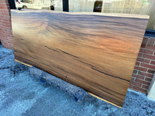 Close-up view of a live edge acacia wood slab dining table top, showcasing its natural wood grain, rich tones, and unique, irregular edges that highlight the organic beauty of the wood