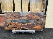 A Live Edge Dining Table Top made from Ironwood, featuring a rich, dark wood grain with natural, raw edges, complemented by an opaque black epoxy resin filling that contrasts beautifully with the wood. The epoxy creates a sleek, modern finish, highlighting the unique characteristics of the wood while adding a contemporary touch.