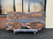 A Live Edge Dining Table Top made from Ironwood, featuring a rich, dark wood grain with natural, raw edges, complemented by an opaque black epoxy resin filling that contrasts beautifully with the wood. The epoxy creates a sleek, modern finish, highlighting the unique characteristics of the wood while adding a contemporary touch.