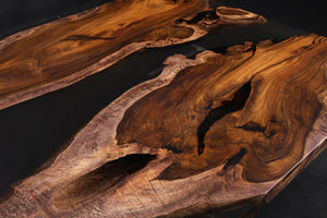 A Live Edge Dining Table Top made from Ironwood, featuring a rich, dark wood grain with natural, raw edges, complemented by an opaque black epoxy resin filling that contrasts beautifully with the wood. The epoxy creates a sleek, modern finish, highlighting the unique characteristics of the wood while adding a contemporary touch.