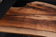 A Walnut wood dining table top featuring rich, dark brown tones and striking grain patterns, enhanced with black epoxy resin filling the natural cracks and imperfections. The smooth, polished surface showcases the contrast between the wood’s organic beauty and the sleek, modern black epoxy.